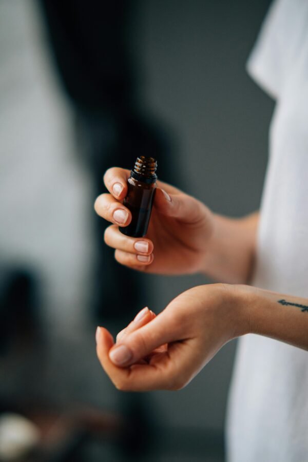 Hands applying essential oil from a small bottle. Close-up, blurred background for an intimate, calming effect.