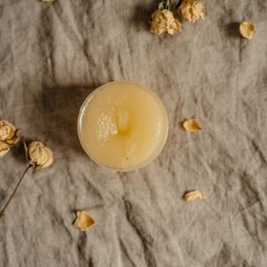 A top-view image of a natural ointment surrounded by dried roses, ideal for skincare concepts.