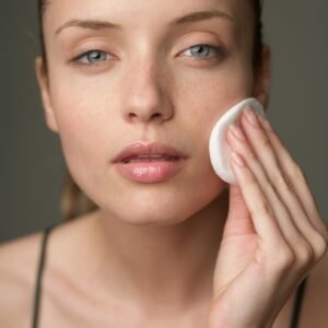 Young woman using a cotton pad for skincare, highlighting beauty routine.