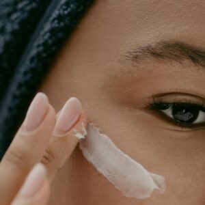 Extreme close-up of a woman applying cream to her cheek for healthy skin care.