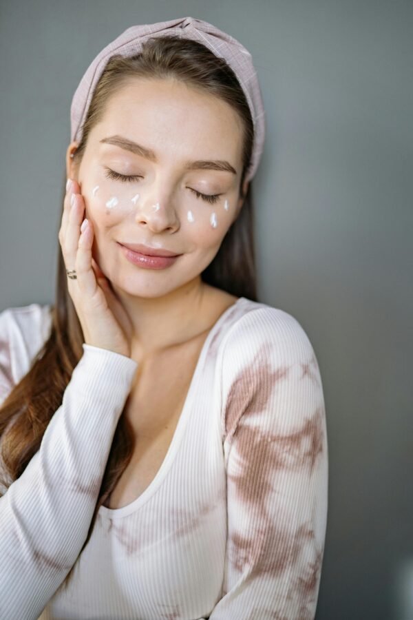 Relaxed woman enjoying skincare routine with cream on her face.