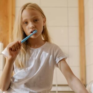 A young girl brushes her teeth, promoting daily dental care habits.