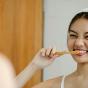 Smiling woman with toothbrush reflects joyful wellness morning routine.