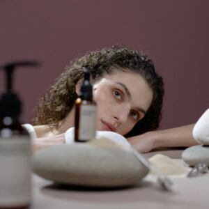 A woman with natural beauty surrounded by cosmetics and stones, creating a soothing atmosphere.