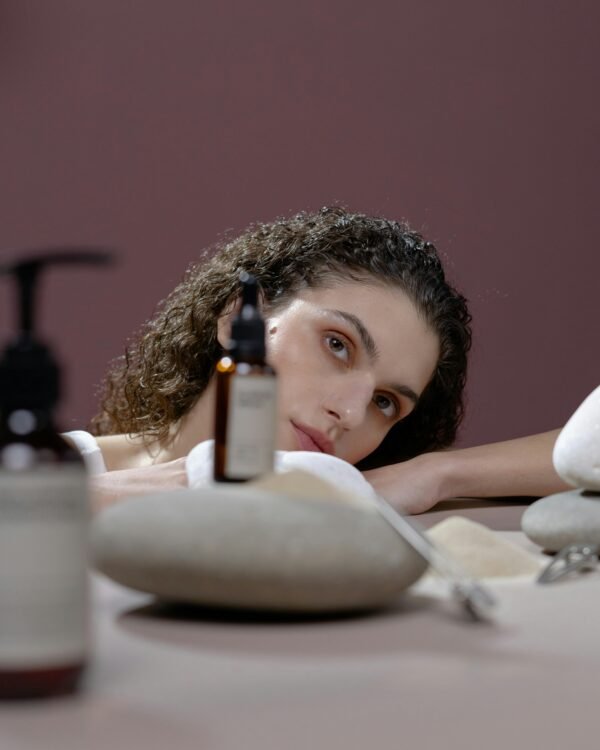 A woman with natural beauty surrounded by cosmetics and stones, creating a soothing atmosphere.