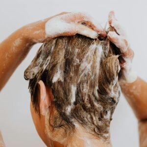 Close-up of a woman washing hair with foam shampoo, focused on hygiene and care.